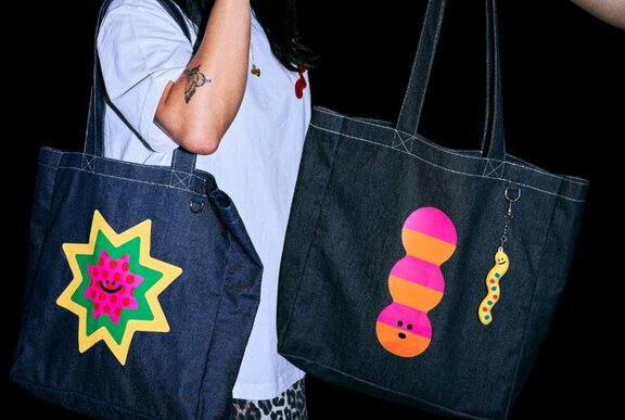 Two denim tote bags, with bright motifs printed on the side of them.