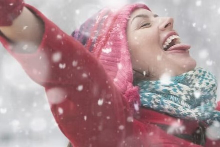 A woman in a red coat and beanie enjoying the snow.