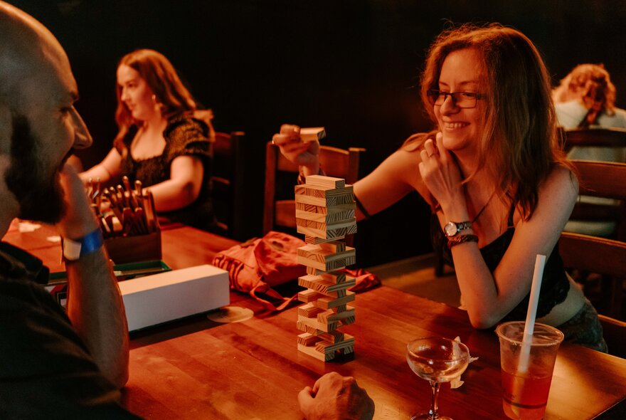 Gamers playing Jenga at a shared table.