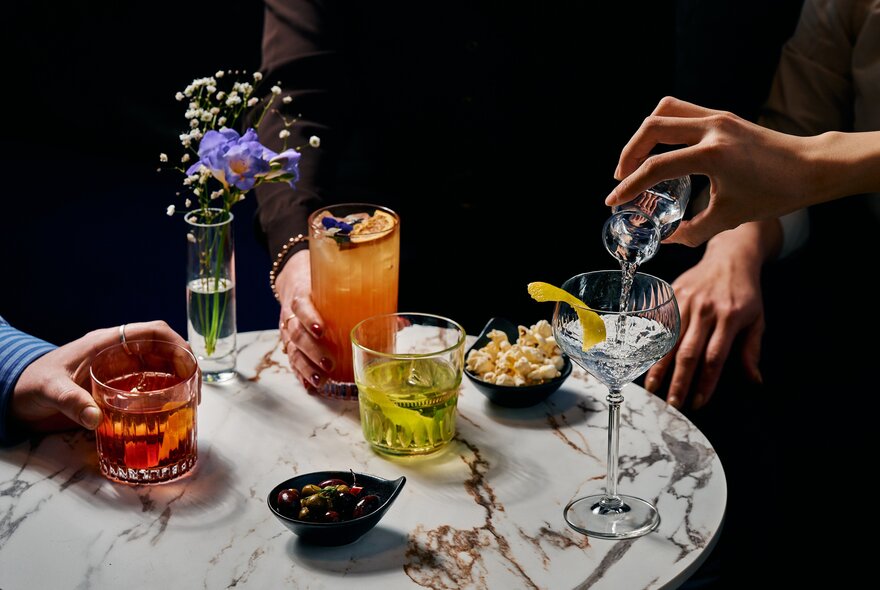 A selection of cocktails on a small, round marble table.