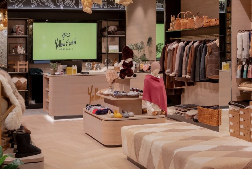 The interior of Yellow Earth at the Melbourne Emporium, with hanging shelves on the side with sheepskin jackets and a beige ottoman in the middle of the store.