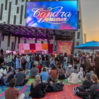 People sitting down in Federation Square at sunset. 