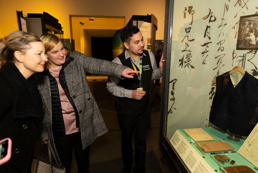 Two people on a tour at the Immigration Museum, the tour guide showing them a room of museum pieces.