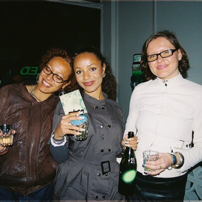 Three women posing for a photo with drinks in their hands.