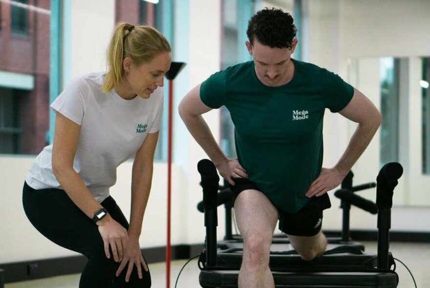 Person exercising and being guided by an instructor while using a Megaformer machine.