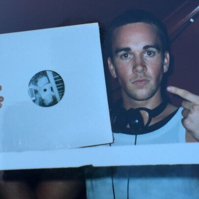 An image of DJ Grant Smillie when he was a young man, holding up a vinyl record.