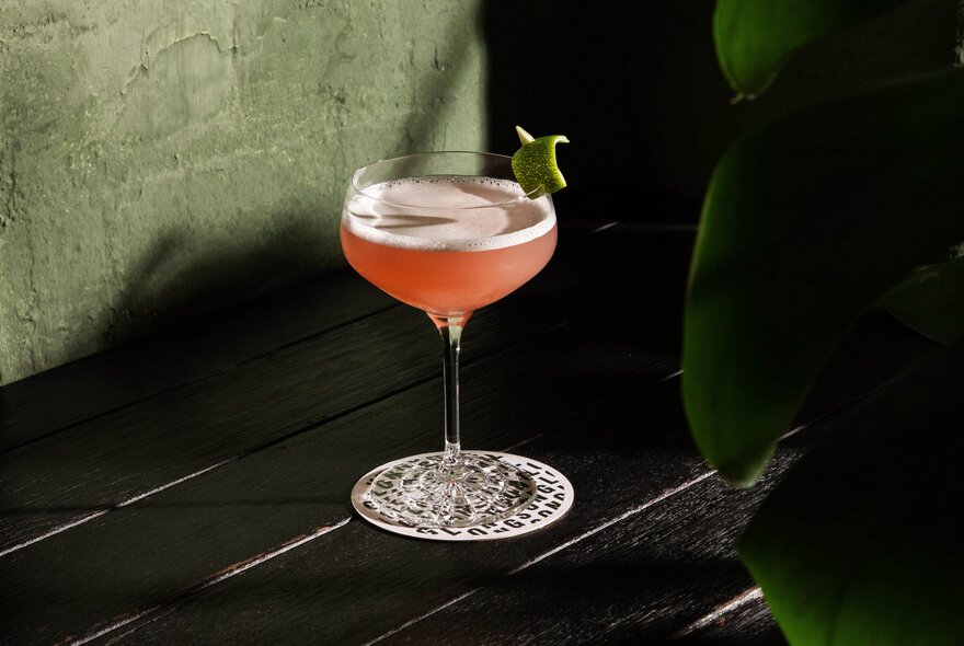 A pink cocktail in a stemmed coupe glass.