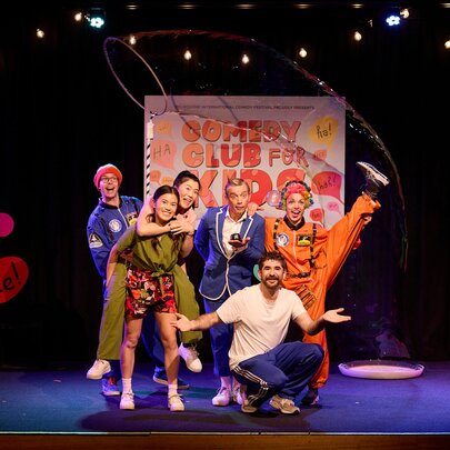 A kids comedy troupe performing on stage in fun poses. 