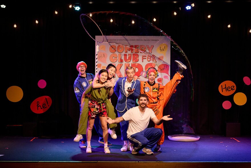 A kids comedy troupe performing on stage in fun poses. 