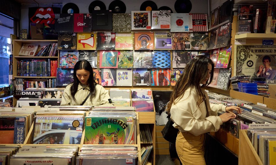 Two friends are sorting through records in a shop.