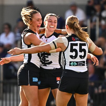 Three Carlton AFLW players in a group hug on the footy field.