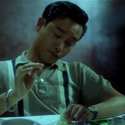 A still from the movie, Days of Being Wild, showing a young man in a 60's style polo shirt, seated at a table.