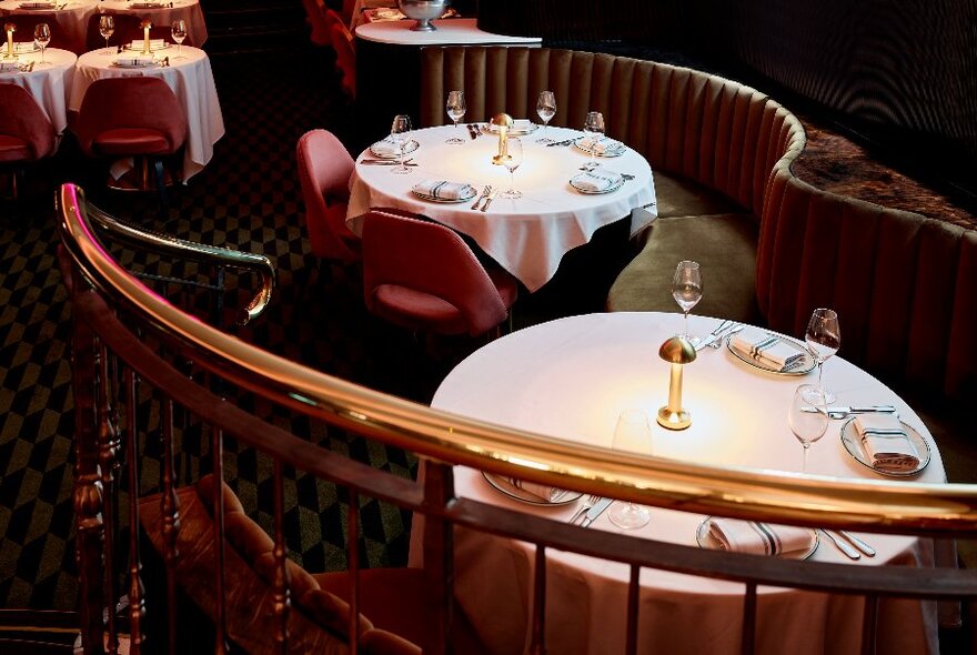 Curved banquette seating and tables set with napery, glasses and cutlery.