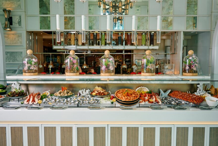 The dinner buffet with food laid out in front of a kitchen counter at a glamourous restaurant.