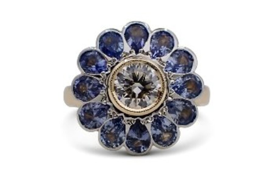 A ring with amethyst stones set in a floral shape around a central round diamond. 