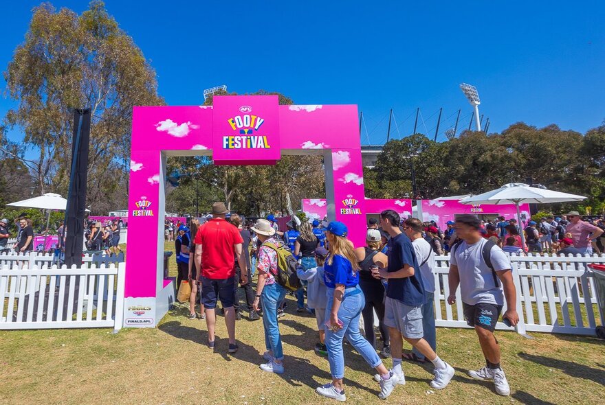Crowds walking through a pink festival entrance.