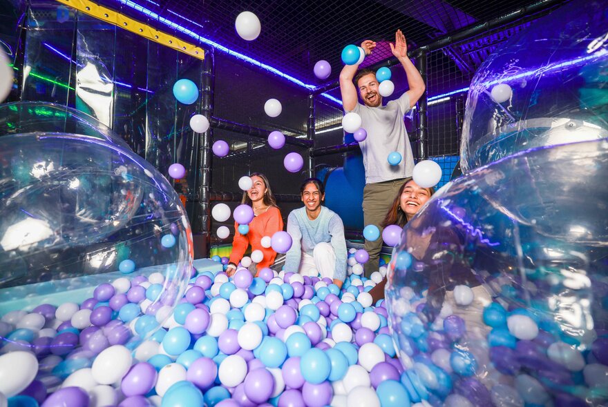 People playing in a pen full of balls and bubbles.