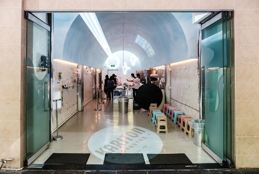 A narrow ice cream shop with a domed concrete ceiling and projections on the walls.