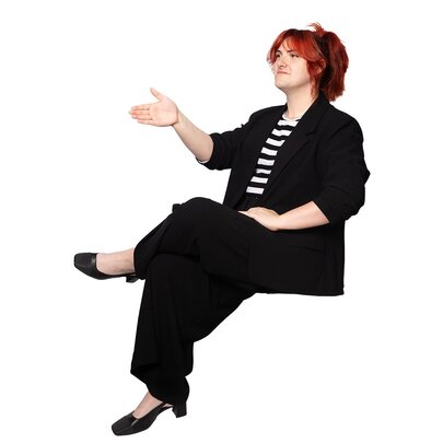 Woman wearing a black suit with striped top, seated with her hand poised to shake.