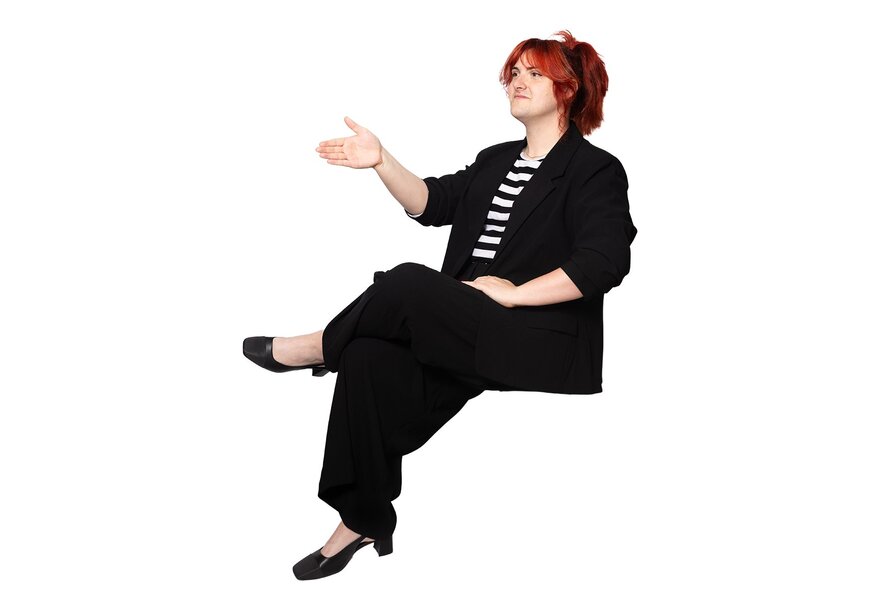 Woman wearing a black suit with striped top, seated with her hand poised to shake.