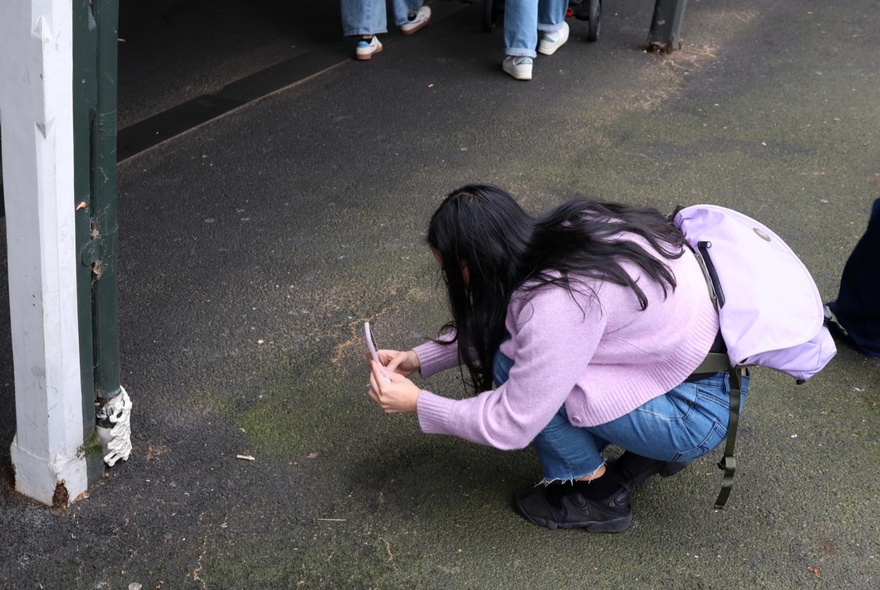 Woman taking a photo of a detail of a post.
