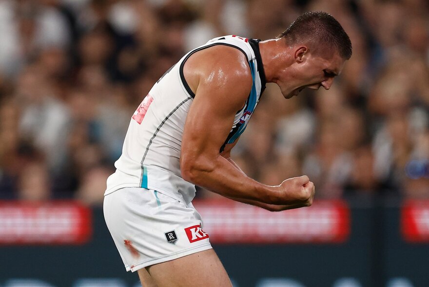 Port Adelaide AFL football player with arms clenched during a match.