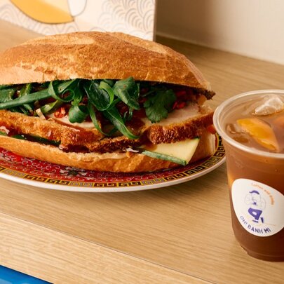 Banh mi sandwich on a plate with an iced coffee.