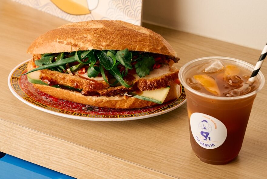 Banh mi sandwich on a plate with an iced coffee.