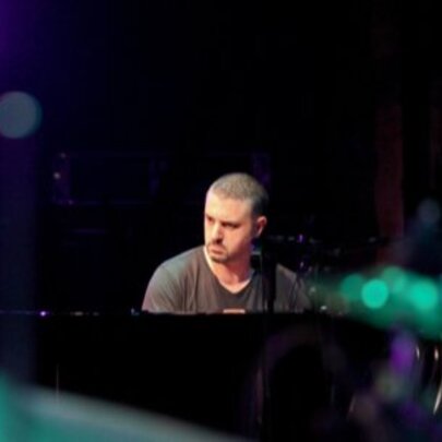 Pianist Phil Turcio, seated at the piano with glowing lights.