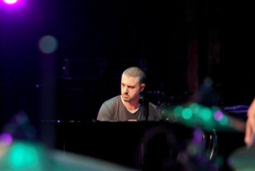 Pianist Phil Turcio, seated at the piano with glowing lights.