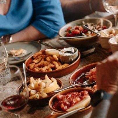 People seated at a restaurant table with platters of food and glasses of wine before them.