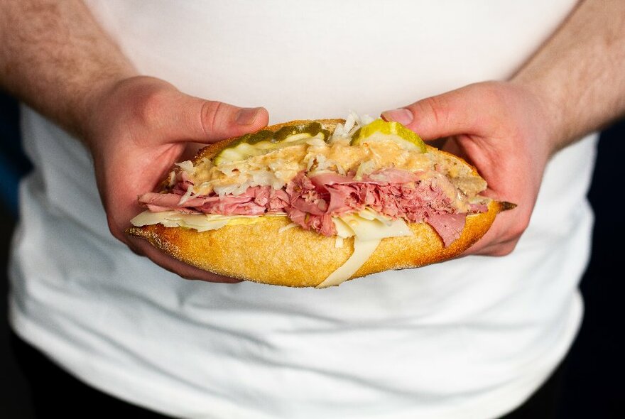 Hands holding a stuffed meat roll.