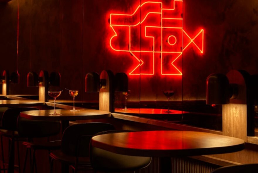 Dark table settings with candles and red neon sign in the background.