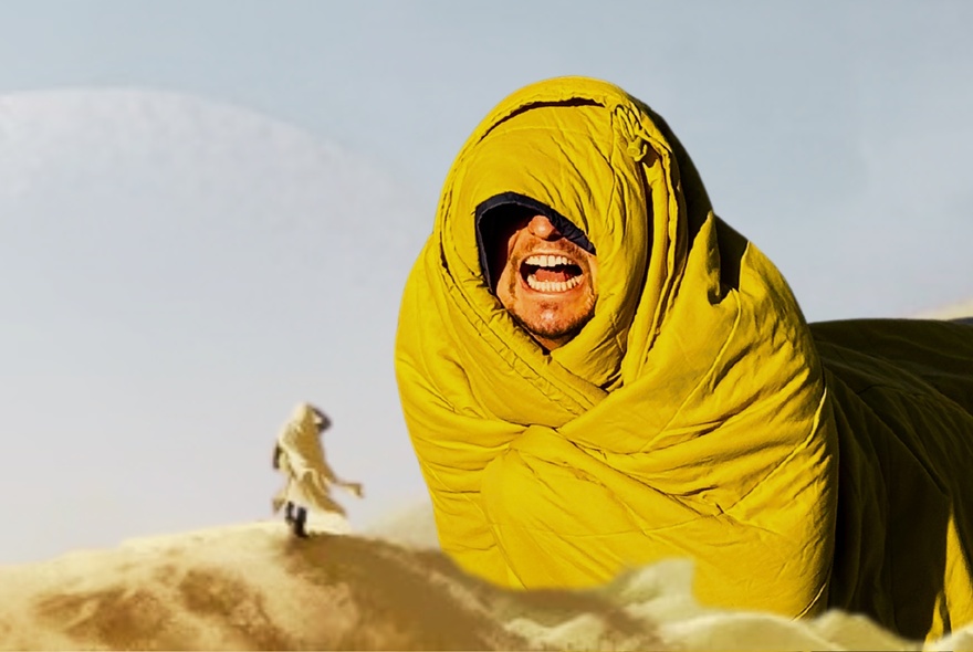 Dune-inspired image of a man wrapped in a yellow sleeping bag.