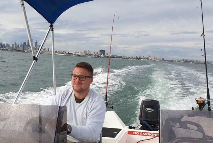 A man driving a fishing speed boat out in open water.