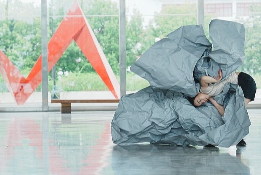 Person encased in grey fabric in an installation space.