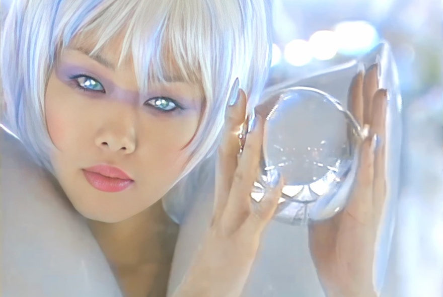 A futuristic looking woman with bobbed silvery platinum blonde hair and laser eyes holding a glass ball.