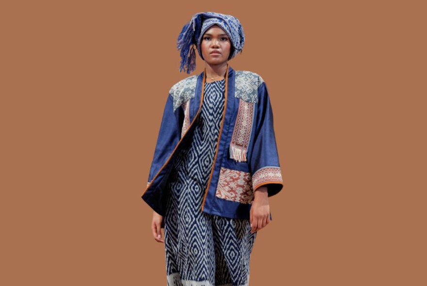 Fashion model wearing a turban, flowing jacket with patchwork and a patterned long dress.