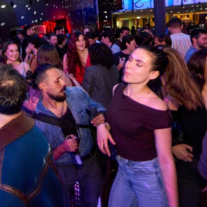 A crowded indoor dance floor with people dancing under disco-style lighting.