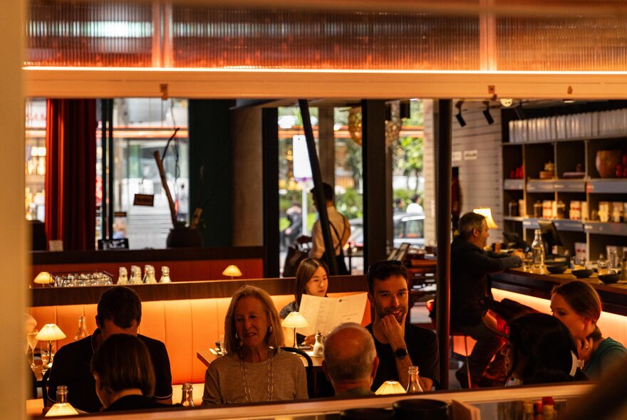 Diners in a restaurant with a mirrored wall, a single man seated at the bar. 