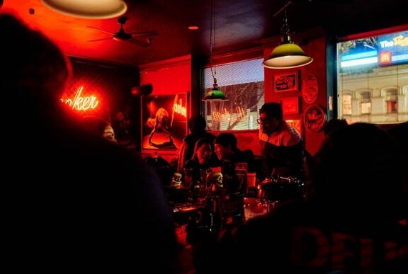 People sitting in a dark, red-lit bar.