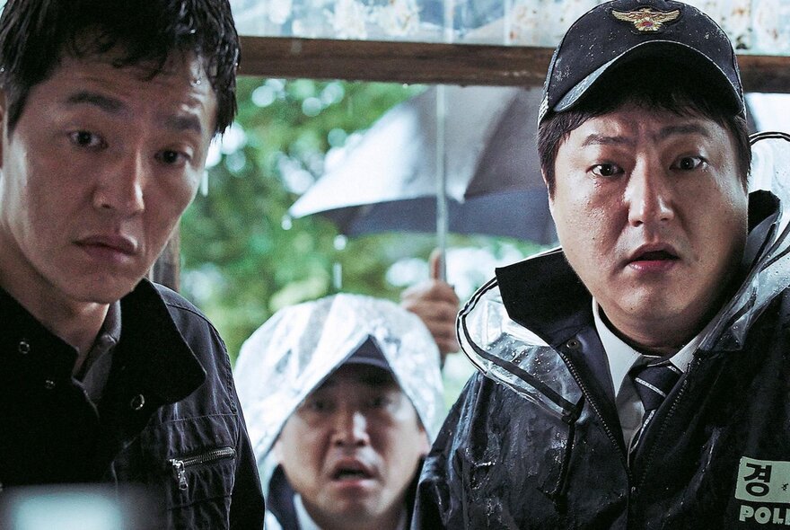 A still from a Korean horror film showing two police officers in shock.