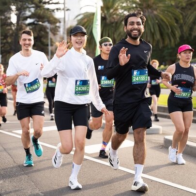 A group of people running as part of an organised event, waving.