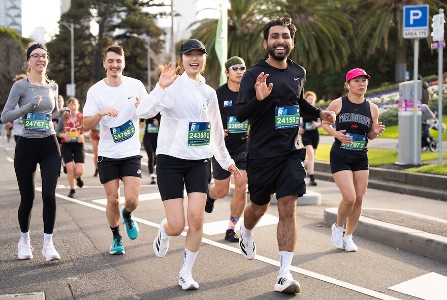 A group of people running as part of an organised event, waving.