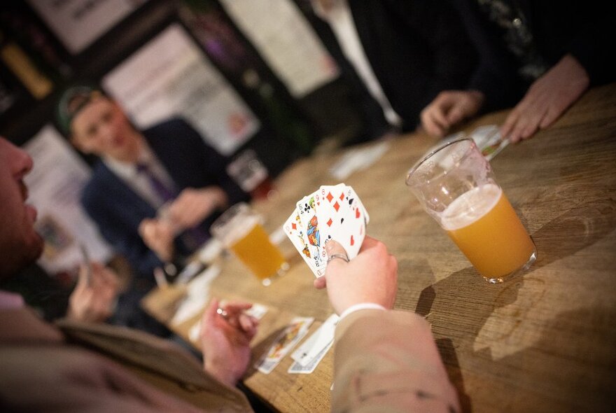 Looking across a table at people playing cards and drinking beer. 