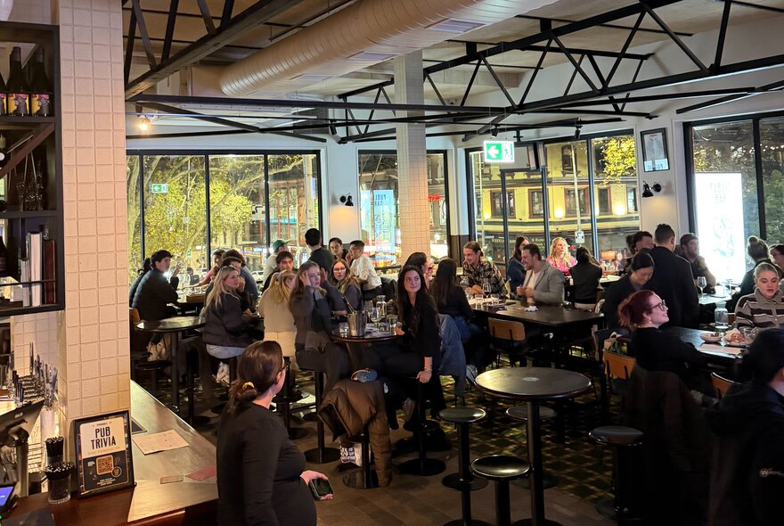 A crowd of people seated at tables inside Springrock Public Bar enjoying drinks and dining, taking part in a trivia quiz.