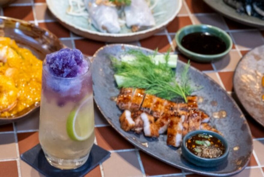 A Thai dish of sliced meat on a plate with a floral drink.