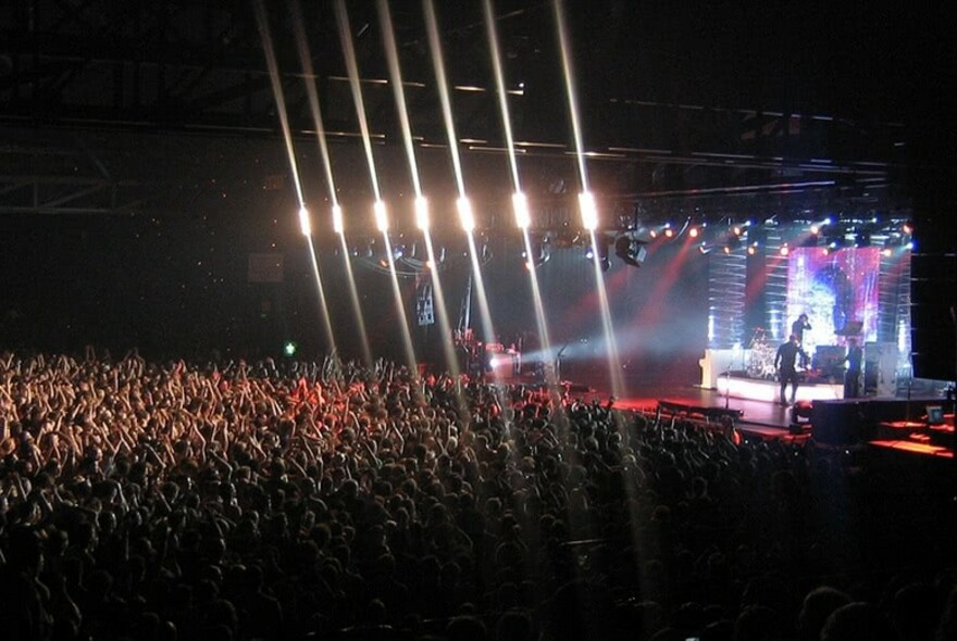 Tightly packed crowd watching a band play on stage.