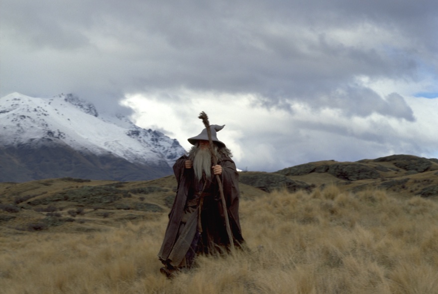 A still from the movie Lord of the Rings: The Fellowship of the Ring, showing Gandalf the Grey walking through a rugged mountain scene.