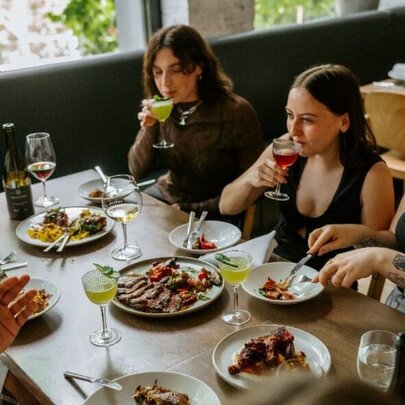 People seated at a restaurant table dining from shared dishes.